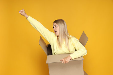 Concept of delivery and gift, young woman in box on yellow backgroundの写真素材