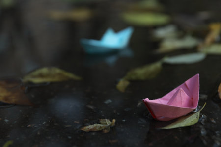 Paper boats in puddle outdoors in rainy weatherの写真素材