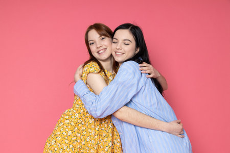 Two beautiful young women, sisters - twins on pink backgroundの写真素材