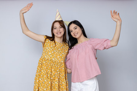 Two beautiful young women, sisters - twins on light gray backgroundの写真素材