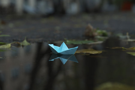 Paper boat in puddle outdoor in rainy weather