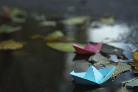 Paper boats in puddle outdoors in rainy weatherの写真素材
