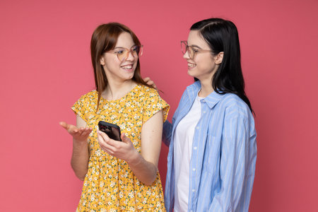 Two beautiful young women, sisters - twins on pink backgroundの写真素材