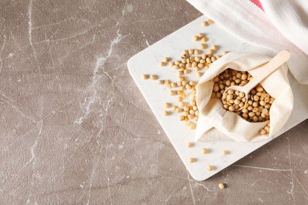Wooden spoon with soy seeds on gray textured table