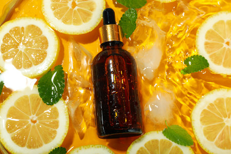 Cosmetic bottle, lemon slices, mint and ice
