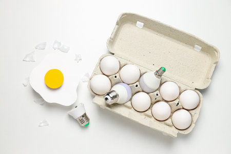 Eggs and bulbs on white background, top view