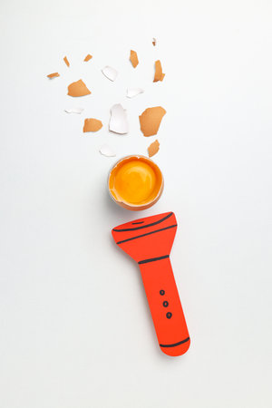 Creative composition with flashlight, egg and egg shells