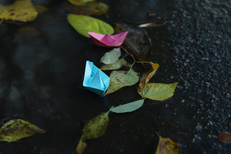 Paper boats in puddle outdoors in rainy weatherの写真素材