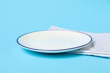 Napkin and empty plate on blue background, close upの写真素材