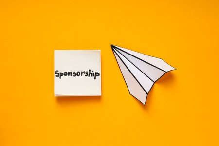 Concept of sponsorship with paper plane on yellow backgroundの写真素材