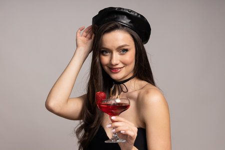 Young woman with cocktail on light gray background