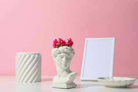 Decor concept with ancient head on white table against pink backgroundの写真素材