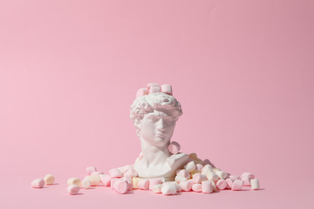 Ancient head with marshmallow on pink backgroundの写真素材