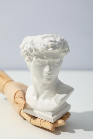 Wooden hand and ancient head on white tableの写真素材