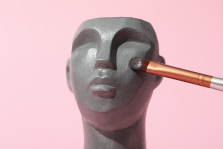 Decorative head with makeup brush on pink backgroundの写真素材