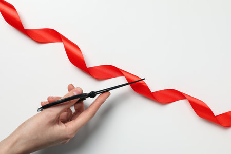 Female hand cut red ribbon on white backgroundの写真素材
