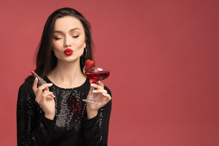 Beautiful girl with lipstick and cocktail in her handsの写真素材