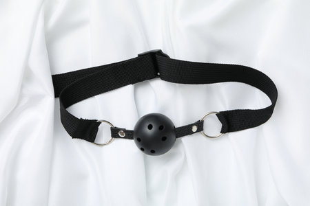 Sex toy gag on a white silk backgroundの写真素材