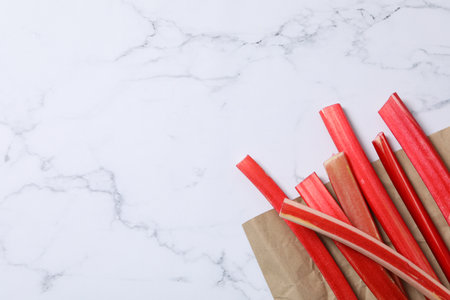 Rhubarb on craft paper, white marble background, space for textの写真素材