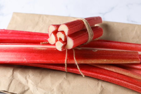 Rhubarb with twine on kraft paper, white marble background, close upの写真素材