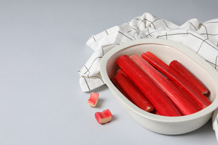 Rhubarb stalk in bowl and white checkered towel on gray background, space for textの写真素材