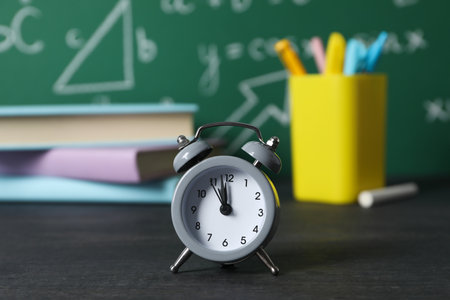 Clock on the table on the background of school suppliesの写真素材