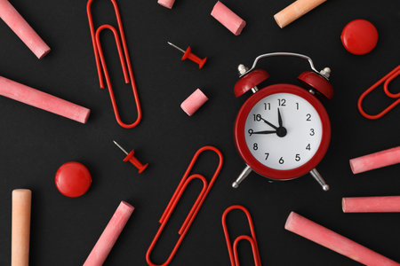 Multicolored pieces of chalk with a clock on a black backgroundの写真素材