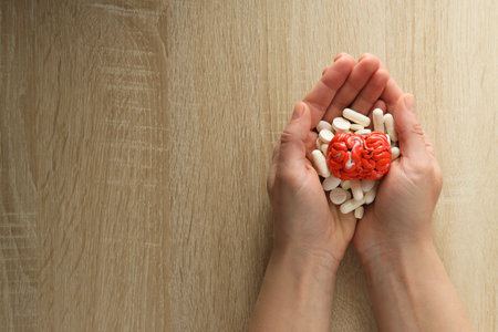 Pills and decorative brain in female hands with space for textの写真素材