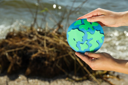 Paper planet Earth in hands on the background of a polluted beachの写真素材