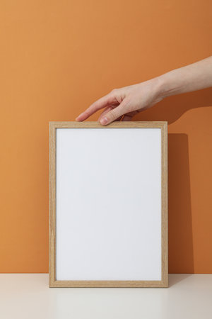 Hand holding a photo frame on a brown background