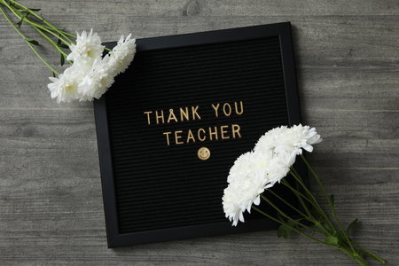 Black frame with text and white flowers on wooden background