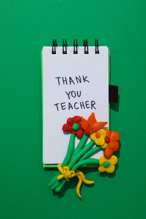 Notepad and plastic flowers on green backgroundの写真素材