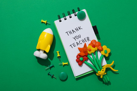 Notepad, toy and plastic flowers on a green background, flat layの写真素材
