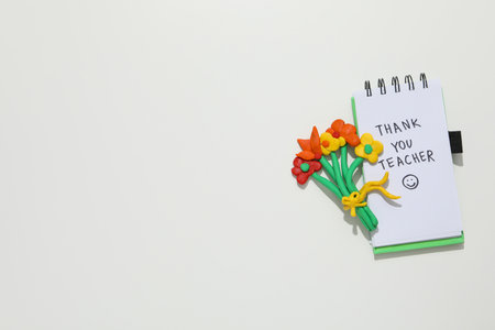 Notepad and plastic flowers on white background, space for textの写真素材