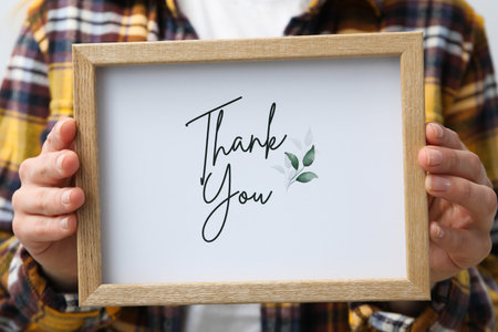 Inscription thank you on paper in a wooden frame in female handsの写真素材