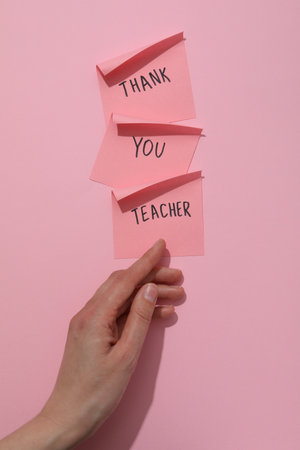 notes with text and female hand on pink backgroundの写真素材