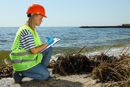 A woman in a hard hats investigates river pollutionの写真素材