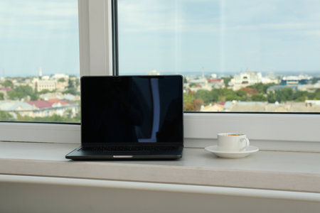 A laptop and a cup of coffee on the windowsillの写真素材