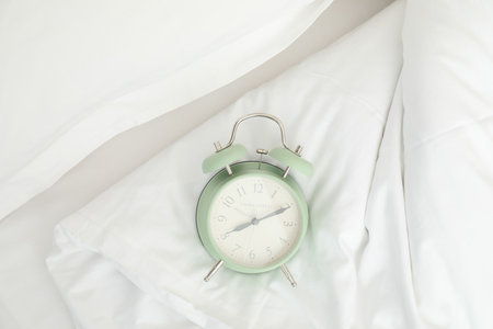 An alarm clock on a white bed