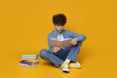 A teenager reads a book on a yellow background