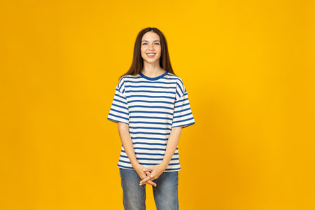 A young woman in a striped T-shirt is smiling on a yellow backgroundの写真素材