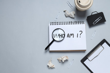 Lens on notepad with text, paper glass and office supplies on gray background, space for text