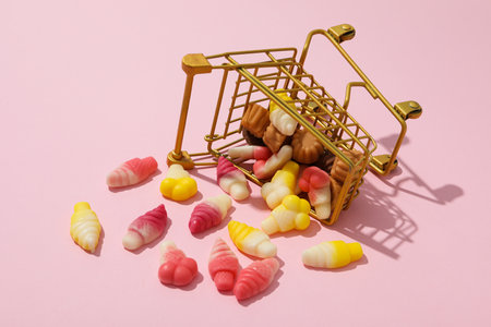 Jelly candies in shopping trolley on pink backgroundの写真素材