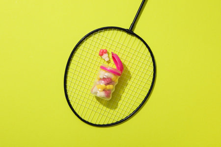Jelly candies in jar on tennis racket on green background, top viewの写真素材
