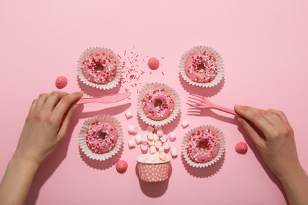 Many pink donuts on a pink background with handsの写真素材