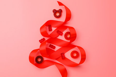 Jelly candies and christmas tree shaped ribbon on pink background, top viewの写真素材