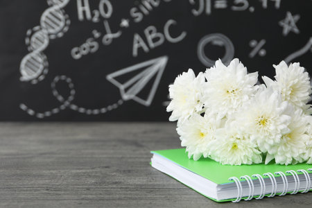 Flowers on a notebook on the background of a dark school boardの写真素材