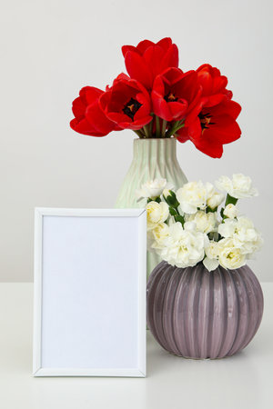 Vertical desktop photo frame with flowers nearby on the tableの写真素材