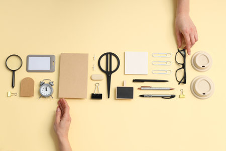 Stationery mockup with female hands, o'clock and different stationery on beige background, top viewの写真素材