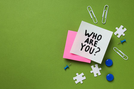 Who Are You question text on sticky note with office supplies on green backgroundの写真素材